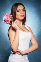 sourire invitant. portrait d'une jeune femme heureuse tenant une fleur photo