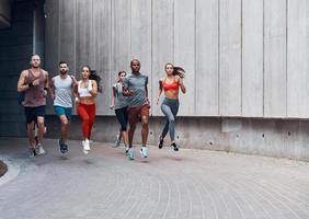 toute la longueur des jeunes en vêtements de sport faisant du jogging tout en faisant de l'exercice à l'extérieur photo