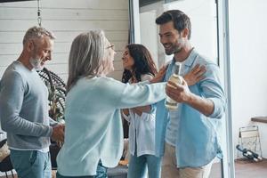 parents seniors souriants rencontrant un jeune couple à l'intérieur de la maison photo