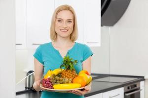 uniquement des aliments sains. cheveux blonds mûrs femme tenant une assiette avec des fruits et souriant à la caméra photo