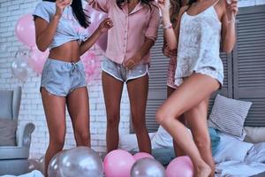 belles jambes. gros plan de quatre jeunes femmes en pyjama se liant lors d'une soirée pyjama photo