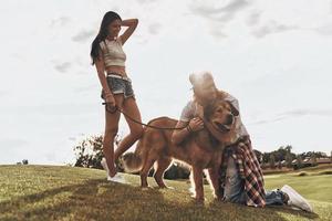 leur meilleur ami. beau jeune homme embrassant son chien tout en passant du temps libre avec sa petite amie dans le parc photo