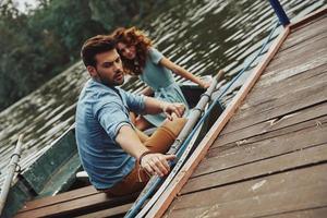 commencer un voyage romantique. beau jeune couple se prépare à ramer un bateau tout en profitant de leur rendez-vous à l'extérieur photo