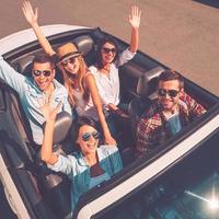 nous voyageons toujours ensemble vue de dessus de jeunes gens heureux profitant d'un voyage en voiture dans leur cabriolet blanc et levant les bras photo