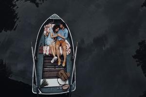 couple d'amoureux en bateau. vue de dessus du beau jeune couple embrassant et souriant en position couchée dans le bateau photo