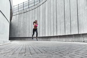 plein d'énergie. toute la longueur de la jeune femme en vêtements de sport jogging tout en faisant de l'exercice à l'extérieur photo