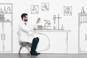 expérience scientifique. jeune homme confiant en uniforme blanc assis contre un mur et faisant une expérience scientifique dans un laboratoire dessiné au crayon photo