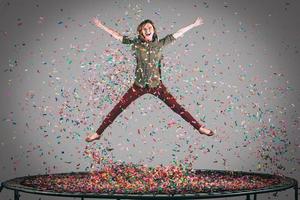 comme une étoile. tir en l'air d'une belle jeune femme sautant sur un trampoline avec des confettis tout autour d'elle photo