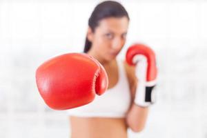 femme boxe. jeune femme confiante dans des gants de boxe tendant la main et regardant la caméra photo