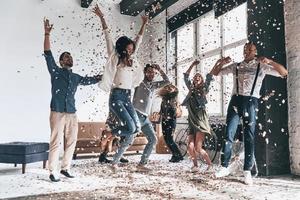 traîner ensemble. toute la longueur de jeunes gens heureux dansant tout en faisant la fête avec des confettis volant partout photo