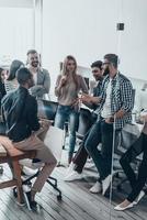 équipe travaillant ensemble. groupe de jeunes gens modernes en vêtements décontractés intelligents discutant de quelque chose dans leur bureau photo