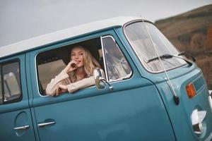 si belle et séduisante jeune femme souriante regardant par la fenêtre de la camionnette tout en profitant du voyage en voiture avec son petit ami photo