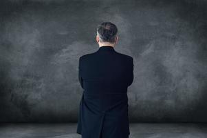 tout sur la confiance. vue arrière d'un homme d'affaires mature gardant les bras croisés en se tenant debout sur fond gris avec espace de copie photo