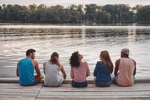 moment insouciant entre amis. vue arrière de jeunes en vêtements décontractés parlant assis sur la jetée photo