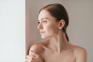 Se sentir belle. jolie jeune femme avec des taches de rousseur sur le visage à l'écart et en gardant la main sur l'épaule photo