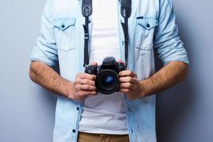 homme avec appareil photo numérique. image recadrée de l'homme avec un appareil photo numérique debout sur fond gris