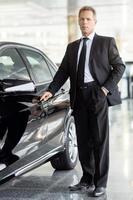 je choisis cette voiture. toute la longueur de l'homme d'affaires mature aux cheveux gris debout près de la voiture et tenant la poignée de porte chez le concessionnaire photo