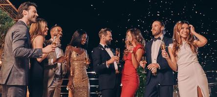 groupe de belles personnes en tenues de soirée communiquant et souriant tout en passant du temps à une fête de luxe photo