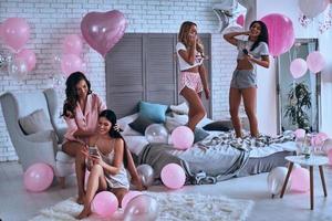 les filles seront des filles. quatre jolies jeunes femmes en pyjama souriant pendant un soin de beauté tout en passant du temps dans la chambre photo