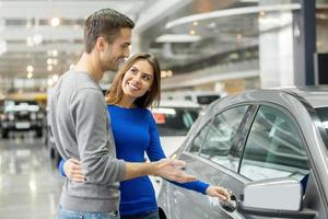 j'aime cette voiture. beau jeune couple debout chez le concessionnaire choisissant la voiture à acheter photo