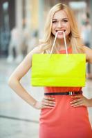 le shopping est amusant. belle jeune femme tenant un sac à provisions dans sa bouche et souriant photo