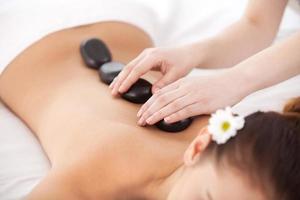 soins de beauté. vue de dessus d'une jeune femme allongée sur le devant pendant que le massothérapeute lui masse le dos avec des pierres de spa photo