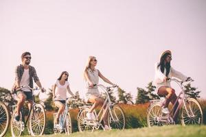 profitant d'une belle journée d'été ensemble. groupe de jeunes faisant du vélo et ayant l'air heureux photo