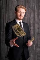 riche et réussi. beau jeune homme en tenue de soirée jetant de l'argent et regardant la caméra photo