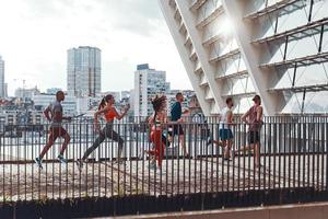toute la longueur des jeunes en vêtements de sport faisant du jogging tout en faisant de l'exercice sur le pont à l'extérieur photo