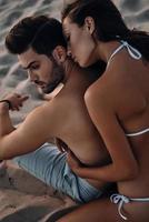 Amour éternel. vue de dessus d'une belle jeune femme embrassant son beau petit ami tout en se relaxant sur la plage photo