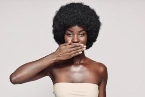 portrait de la belle jeune femme africaine couvrant la bouche avec la main photo
