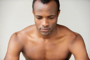 l'homme rêve de jour. beau jeune homme musclé regardant vers le bas en se tenant debout sur fond gris photo