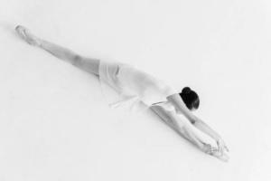 ballerine qui s'étend. vue de dessus de la jeune ballerine en tutu blanc faisant des fentes et des étirements photo