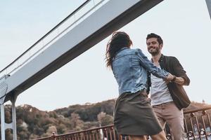 rien d'autre que l'amour. beau jeune couple tenant la main et tournant tout en dansant sur le pont à l'extérieur photo