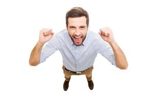 gagnant de tous les jours. vue de dessus d'un jeune homme heureux exprimant sa positivité et faisant des gestes tout en se tenant isolé sur fond blanc photo