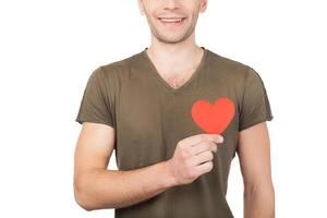 symbole d'amour. image recadrée d'un jeune homme tenant un coeur en papier en se tenant debout isolé sur fond blanc photo