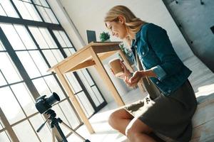 jolie jeune femme en vêtements décontractés souriant tout en travaillant devant une caméra vidéo photo