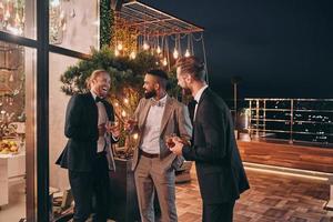 trois hommes bien habillés buvant du whisky et communiquant tout en passant du temps à faire la fête photo