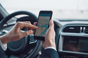 vérifier la direction. gros plan sur un jeune homme utilisant un téléphone intelligent pour vérifier la carte en conduisant une voiture photo