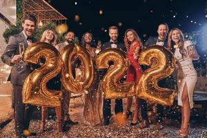 groupe de belles personnes en tenues de soirée portant des chiffres dorés et souriant photo