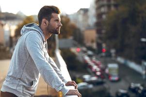 amoureux de sa ville. vue latérale d'un jeune homme pensif dans un casque regardant loin tout en se tenant sur le pont photo