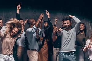 profiter d'une fête incroyable. groupe de beaux jeunes gens dansant avec des flûtes à champagne et ayant l'air heureux photo