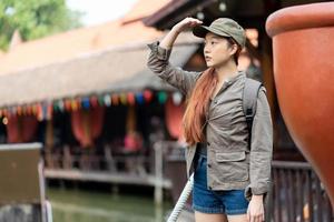 jeune femme asiatique voyageuse avec masque et sac à dos à la recherche de célèbres attractions touristiques en thaïlande photo