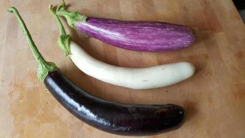 3 aubergines multicolores sur une planche à découper photo