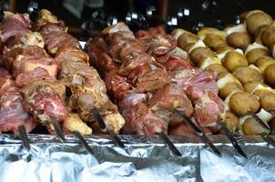 la viande crue et les pommes de terre sont plantées sur des brochettes en métal. le processus de cuisson des shish kebabs. nourriture de camp russe et ukrainienne photo