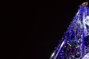 fragment de l'arbre du nouvel an. beaucoup de lumières rondes de couleur bleue sont situées sur un cadre conique photo
