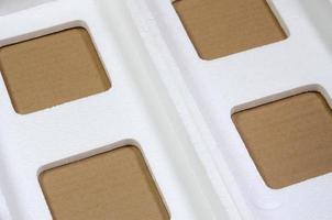 image d'arrière-plan avec du papier carton beige et des boîtes en polystyrène rejetées comme des ordures. le concept de déballage de nouveaux appareils ménagers hors de la boîte en carton photo