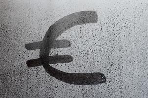 le symbole monétaire de l'euro sur le verre embué de sueur. image de fond abstraite. notion de monnaie euro photo