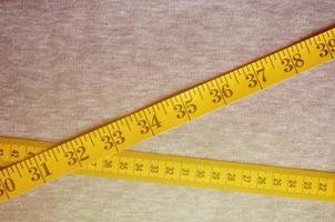 ruban à mesurer jaune se trouve sur un tricot gris photo