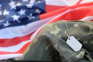 Perles militaires argentées avec étiquette de chien sur le drapeau en tissu des États-Unis et uniforme de camouflage photo